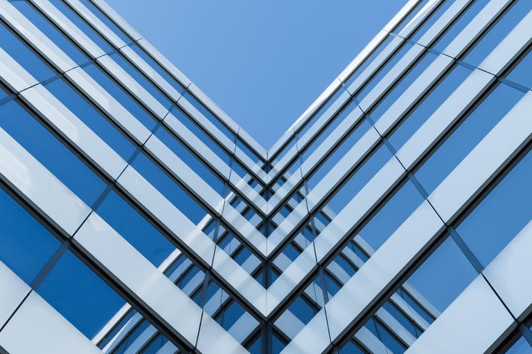 Fachada de edificio moderno de vidrio con líneas geométricas fuertes, destacando diseño arquitectónico y construcción urbana