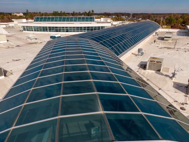 Domo de vidrio estructural en centro comercial con membrana TPO blanca eficiente y atrium de vidrio natural