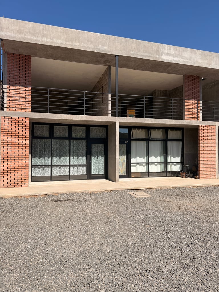 Edificio moderno de dos pisos con fachada de ladrillo rojo, nivel superior de concreto y grandes ventanas de marco negro