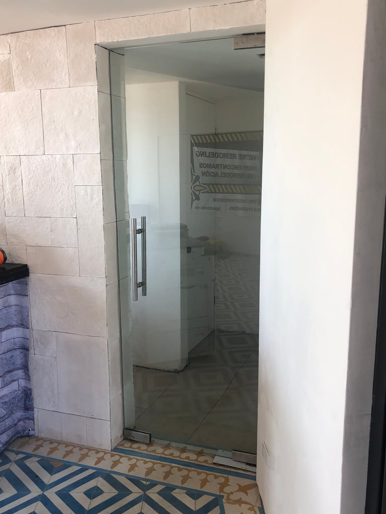 Puerta de ducha de vidrio moderna en baño con paredes de azulejo blanco tipo metro y piso de patrón geométrico